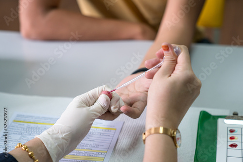 Nurse drawing blood from patient's finger. Close up shot.