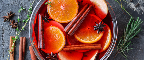 Tasty mulled wine with orange and apple slices in bowl on grey background, closeup