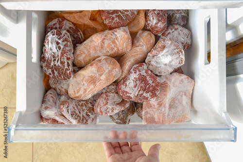 Frozen meat with plastic wrap or cling film in a the freezer. How to freeze fresh meat concept. 