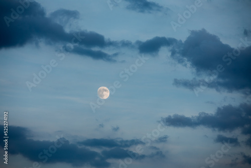 wschód pełnia księżyca na tle niebieskiego nieba i ciemniejszych chmur, full moon