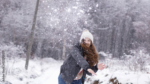 Happy young woman in a snowball fight. Winter holiday spirit.