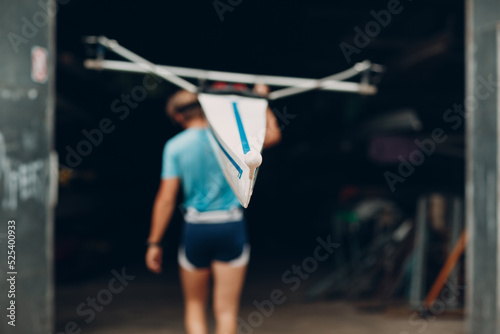 Sportsman single scull man rower prepare to competition carry boat on shoulder with muscular hand