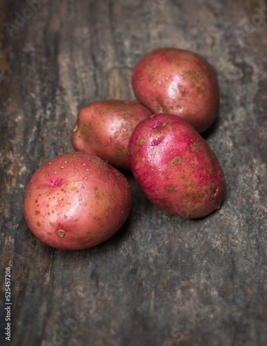 red pontiac potatoes, red-skinned, sweet and white fleshed vegetable on a wooden surface, taken in soft-focus with copy space