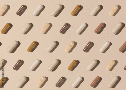 Creative pattern with capsules on light beige top view, hard shadows. Taking supplements