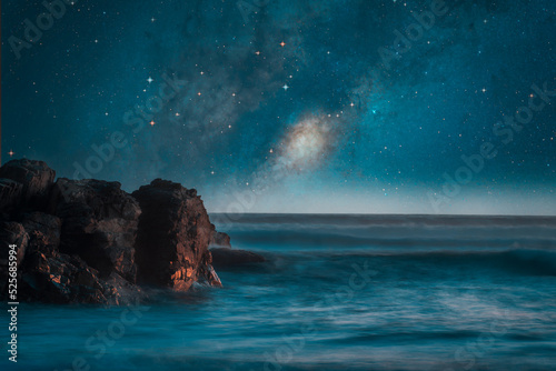 milky way over the sea and rocks on the shore background