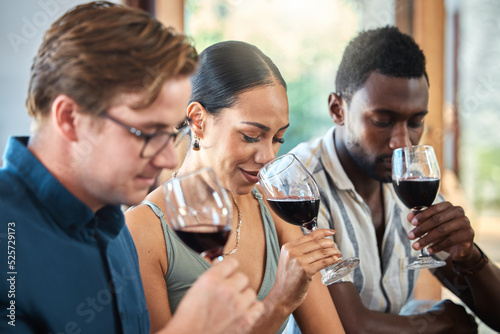 Diversity, luxury and friends wine tasting at a restaurant or vineyard, smelling alcohol in a glass together. Young carefree people bonding and having fun, enjoying a wine tour at a distillery