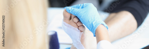 Doctor in medical gloves examines patient leg.