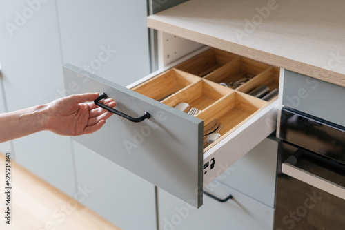 hand open cutlery drawer at contemporary kitchen