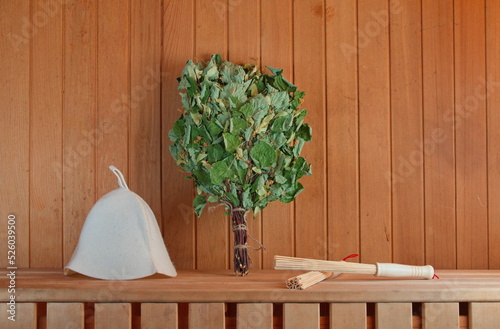 Photo with a composition of sauna items. Traditional felt hat, Birch broom and massage Sticks. Wooden Background. Web Banner. Sauna Conception.