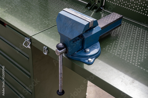 Vise grip stationary. Steel vise fixed on table. Tool for mechanical work. Mechanics desktop. Mechanical equipment for auto mechanic. Blue vise close-up. Concept sale of equipment for mechanic