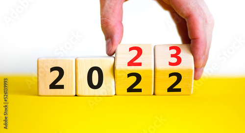 2023 happy new year symbol. Businessman turns cubes, symbolize the change from 2022 to the new year 2023. Beautiful yellow background. Copy space. Business and 2023 happy new year concept.