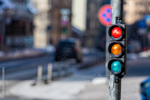 closeup of small traffic semaphore with red light against the backdrop of the city traffic