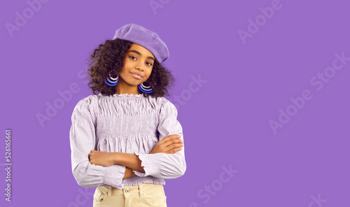 Portrait of smiling African American teen girl isolated on purple studio background look at camera. Happy biracial teenager model in beret and stylish clothing. Copy space. Fashion and style.