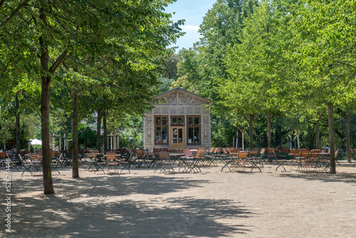 Chairs and tables of a park cafe stand under linden trees in the Fürstenwallpark in Magdeburg.