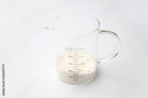小麦粉の入った ガラスの計量カップ 白背景