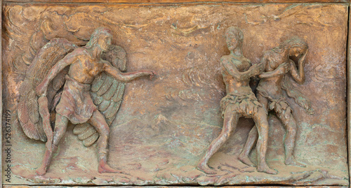 MONOPOLI, ITALY - MARCH 6, 2022: The bronze relief Expulsion of Adam and Eve from Paradise the on the gate of church Chiesa di Sacro Cuore by Wolfgang Stempfele from year 2002.