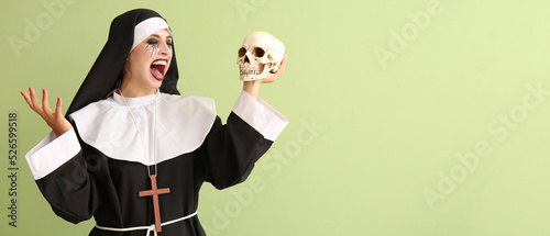 Woman dressed for Halloween as nun with skull on green background with space for text
