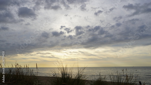 Dünengras mit Blick auf das Meer und dramatischen Sonnenuntergang mit dunklen Wolken 