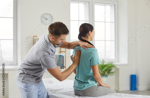 Male chiropractor, physiotherapist or osteopathy specialist examining a female patient with scoliosis or back ache. Physiotherapy, modern orthopaedic therapy, scoliosis treatment concept