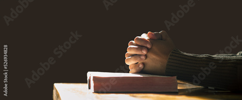 Hands praying of christian put on holy bible with light in morning at wooden table. Close up hands. Christian concept.