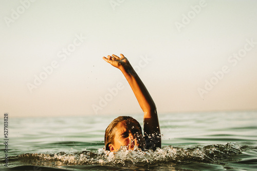 Child drowning in water holding hand above a surface of green water, going deep. Accident in a river, sea, ocean. Dangerous situation on summer coast. Help me concept. Teenage girl drowns. Film filter