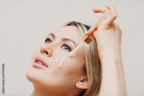 Cosmetic oil royal jelly applying with pipette on face of young woman