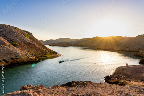Sunrise in a Fjord like in Bandar Khairan with a boat sailing, Sultanate of Oman