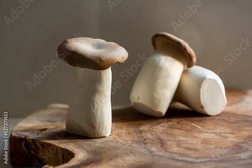 A trio of king oyster mushrooms shot in natural morning light on a wooden baord