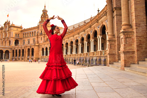 Beautiful teenage woman dancing flamenco in a square in Seville, Spain. She wears a red dress with ruffles and dances flamenco with a lot of art. Flamenco cultural heritage of humanity.