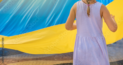 Niña pequeña irreconocible, sujetando la bandera de Ucrania. Fotografía horizontal con espacio para texto.
