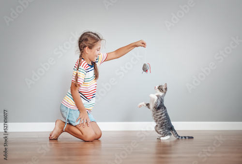 Cute girl playing with her little kitten at home