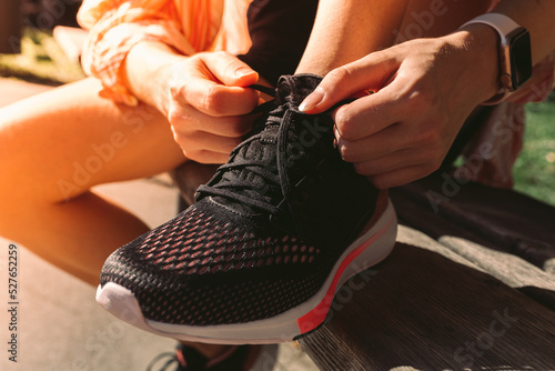 Young woman runner of athletic build, unrecognizable, tying shoelaces on running shoes