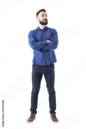 Confident cool young bearded man standing and looking away with crossed hands. Full body isolated on transparent background.