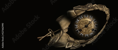An old antique clock with roman numerals on the dial in carved golden frame, isolated on black