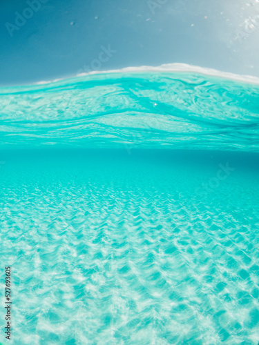 Half underwater shot, clear turquoise water and sunny blue sky. Tropical ocean