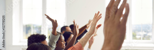 Active multiracial audience raising hands. Happy mixed race multiethnic people sitting in row with hands up to ask coach questions after interesting talk, session, or master class. Header background