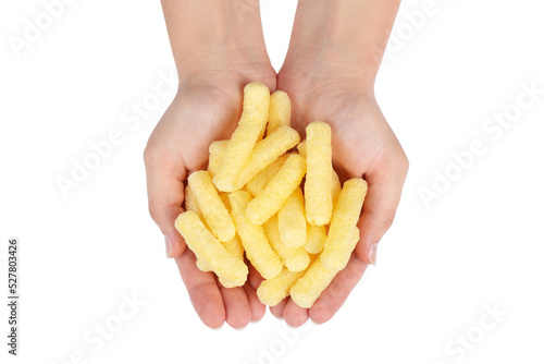 Woman holding pile of tasty corn puffs on white background, top view