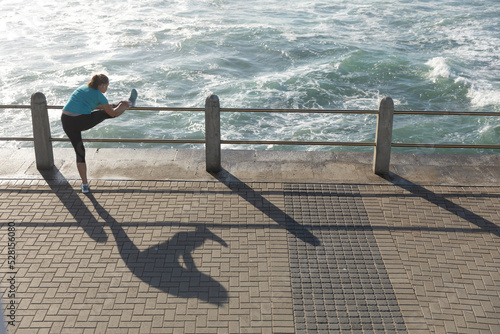 Female jogger stretching on seaside