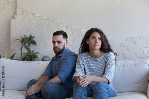 Silent couple sit on sofa staring aside after fight, avoid talk, look deep in thoughts about relationship break up, troubles in relations. Marriage, split, crisis, misunderstanding, quarrels concept