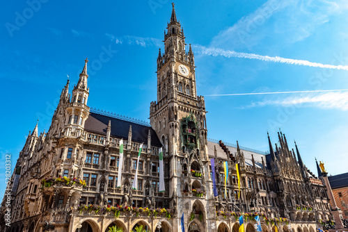 Die im Stil der Neugotik gestaltete Fassade des neuen Rathaus mit Rathausturm in der Altstadt von München in Unteransicht vom Marienplatz aus gesehen bei schönem Sommerwetter und blauen Himmel