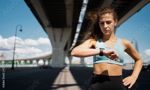 Smart watch on the arm for training, a sporty woman doing fitness exercises on the street