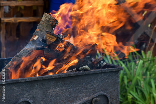 Firewood is burned for barbecue. Embers bright flame. Barbecue with burning firewood. Yellow, bright and warm flame. Open fire.