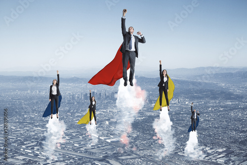 European businessmen and women heroes with cape flying on abstract city background. Success, teamwork, leadership and start up concept.