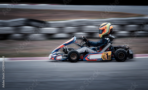 Go kart racing field, racer wearing safety uniform on competition tournament. 