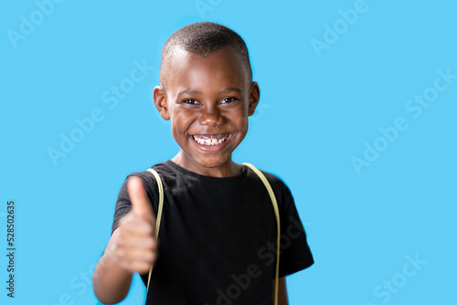 giovane ragazzo nero su sfondo blu con i pollici in su perché è successo qualcosa di buono