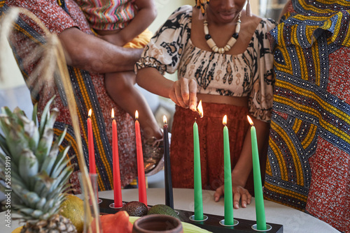 Close-up of African family of four in national costumes burning all seven candles for Kwanzaa holiday