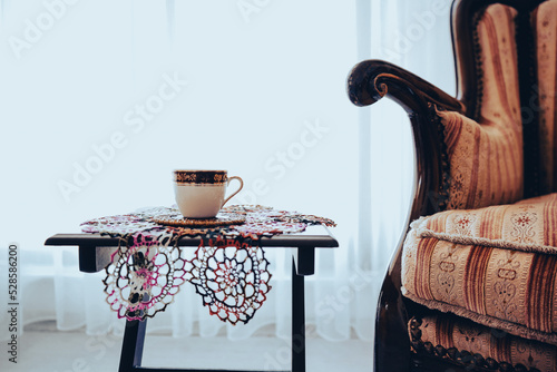 turkish coffee and lace doily under coffee, vintage style armchair wooden, curtain behind them near window