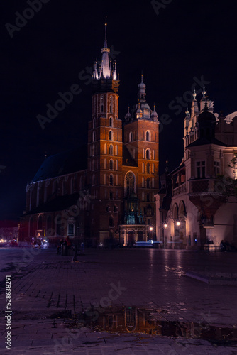 St. Mary's Basilica in Krakow with reflection in a puddle at night | Bazylika Mariacka w Krakowie z odbiciem w kałuży nocną porą