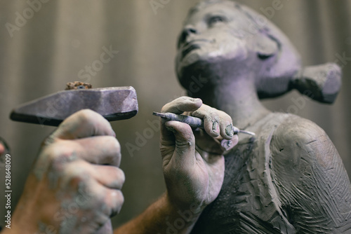 Man sculptor creates sculpt bust human woman sculpture with hammer. Statue craft creation workshop.