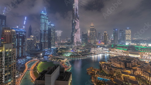 Skyscrapers rising above Dubai downtown night timelapse surrounded by modern buildings aerial top view